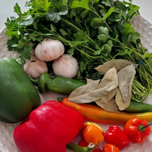 Plateau garni de légumes frais : persil, ail, échalotes, piment et poivrons, utilisés dans la préparation artisanale des sauces Moss Dolli